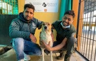 Two people pose with a dog
