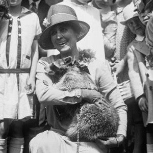 Grace Coolidge with Rebecca raccoon with a group of children looking on