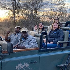 A group of tourists sitting in a car with two guides in the African savanna