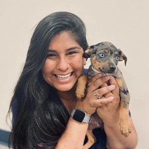 Smiling woman with dark hair holding a puppy