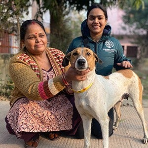 Two women kneeling with a rescued dog, looking at the camera