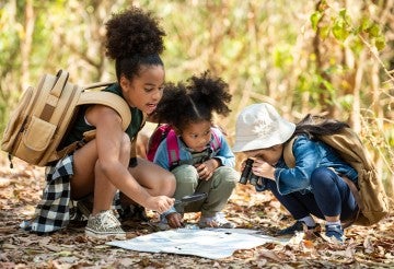 Three kids looking at a map on a nature walk
