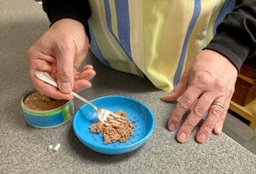 A man mixing cat medication into wet food.