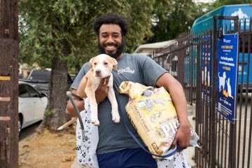 Man holding a puppy and bag of dog food