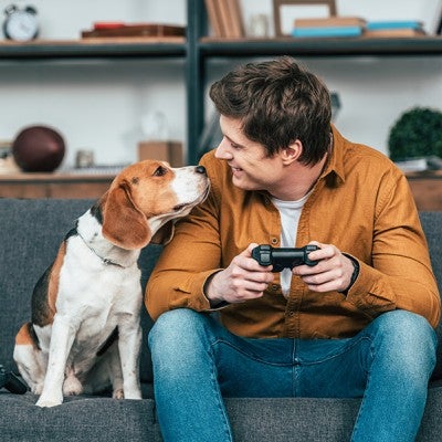 Man and dog sitting on the couch playing video games