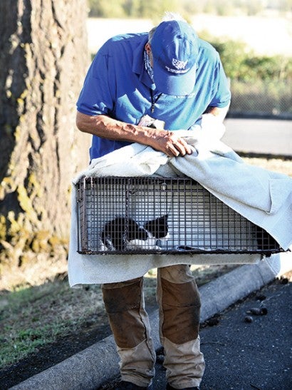 man holding a trap with a kitten inside