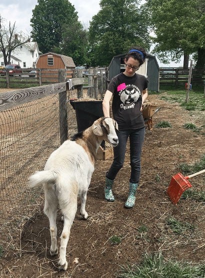 Woman outside with a goat at a farm rescue. 
