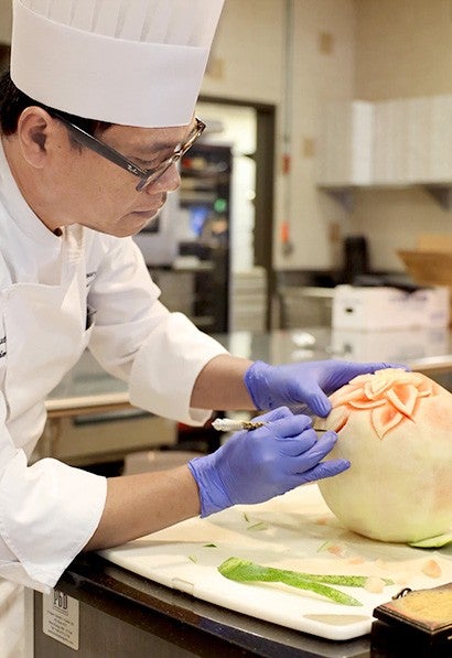 Chef Herlan Manurung carves a melon to demonstrate the art of food preparation.