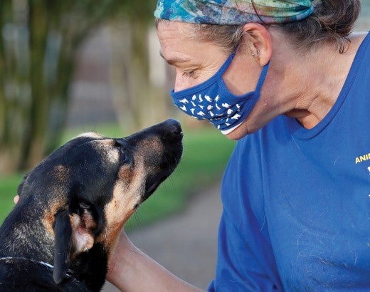 woman wearing mask petting a dog
