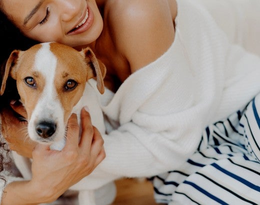 A woman hugs her dog goodbye, but he looks sad and doesn't want her to leave
