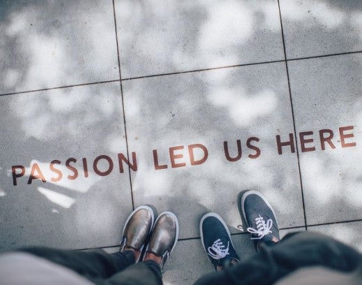 Two people standing in front of text on the floor reading "passion led us here"