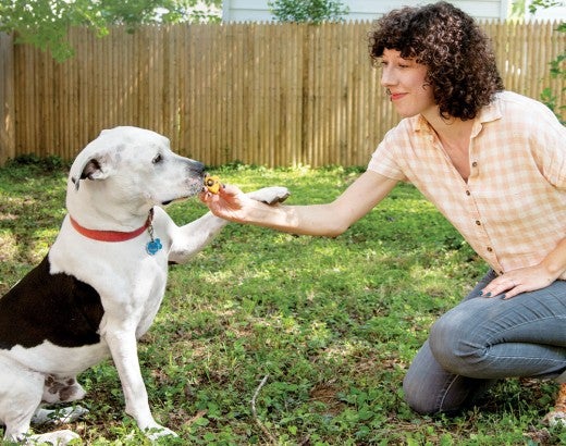 Woman outside with dog, feating him a treat