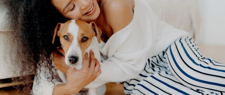 A woman hugs her dog goodbye, but he looks sad and doesn't want her to leave