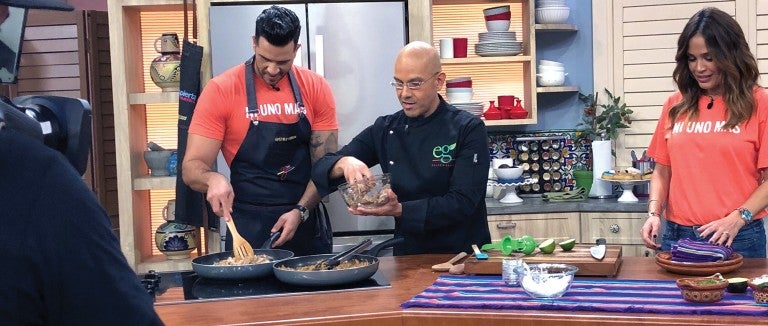 Chef Eddie Garza demonstrating plant-based cooking techniques on a television program.