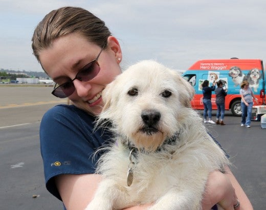 Kelsey Apling, transport assistant from the Humane Society for Southwest Washington, comforts Thunder, a 10 year old schnauzer mix, who just got off the plane. 